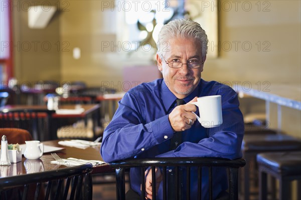 Hispanic cafe owner having cup of coffee