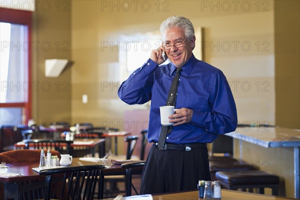 Hispanic cafe owner talking on cell phone