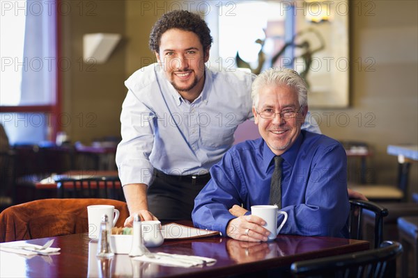 Businessmen smiling together in cafe