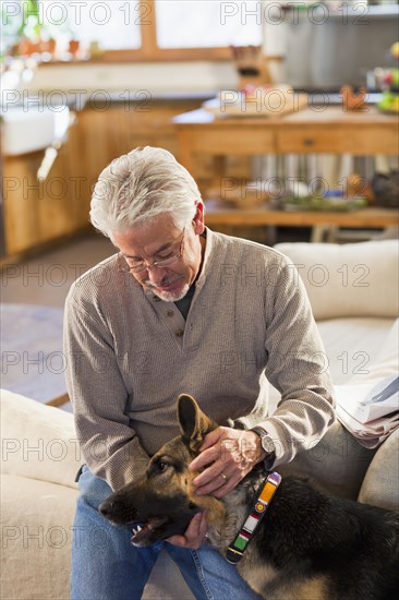 Hispanic man petting dog in living room