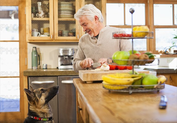 Hispanic man with begging dog in kitchen