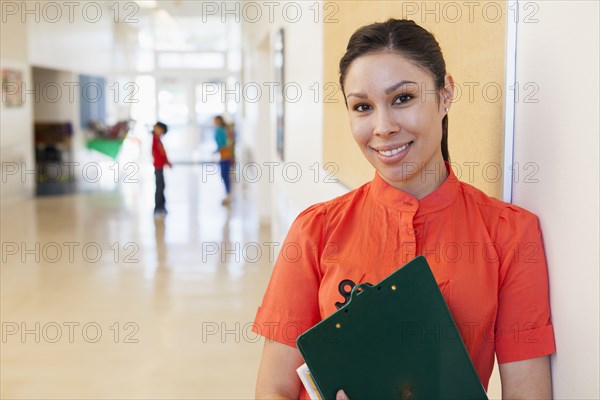 Mixed race teacher holding clipboard in school hallway