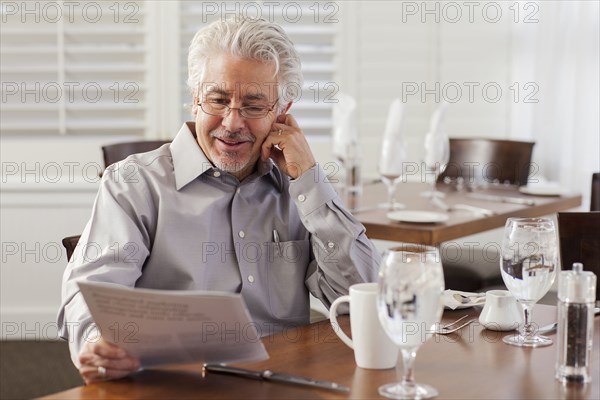 Hispanic businessman reading papers in cafe