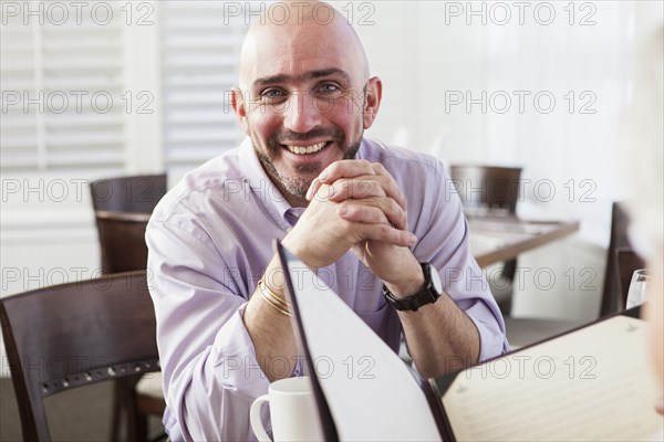 Mixed race businessman smiling in cafe