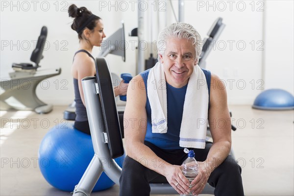 Older Hispanic man smiling in gym