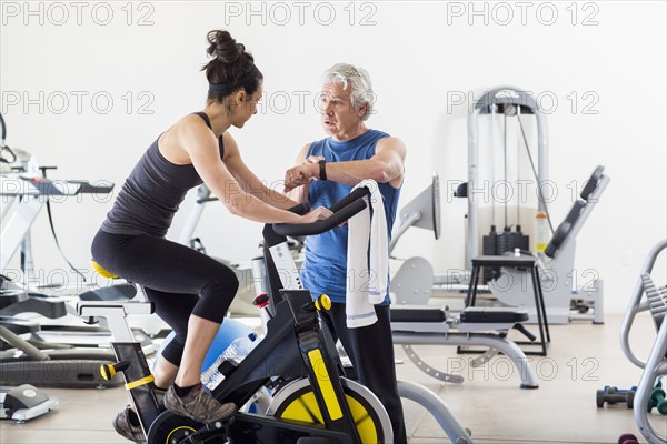 Hispanic trainer working with woman in gym