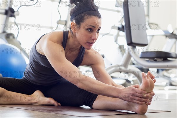 Hispanic woman stretching in gym