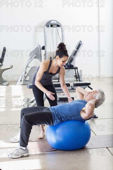 Older Hispanic man working with trainer in gym