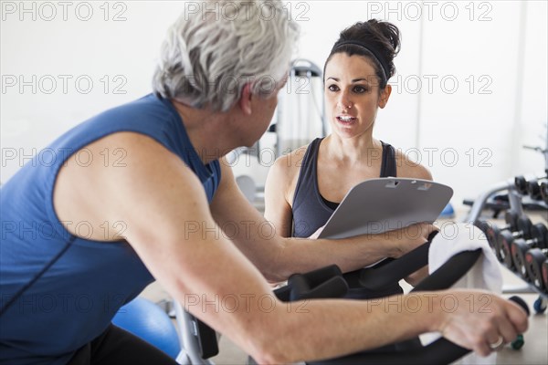 Older Hispanic man working with trainer in gym