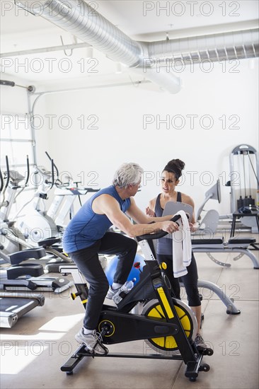 Older Hispanic man working with trainer in gym