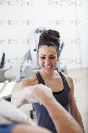 Hispanic man cheering with trainer in gym