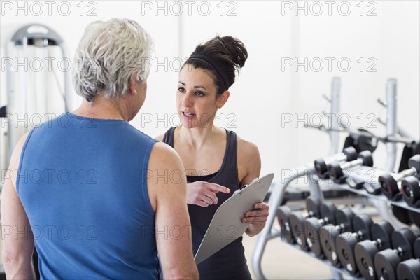 Older Hispanic man working with trainer in gym