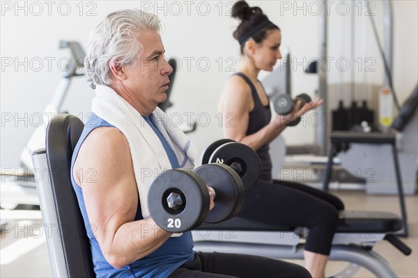 Older Hispanic man lifting weights in gym