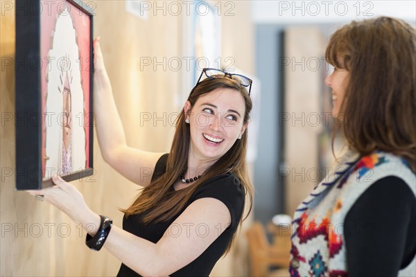 Women hanging painting on wall