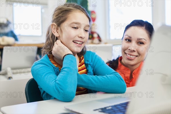 Teacher and student using laptop in library