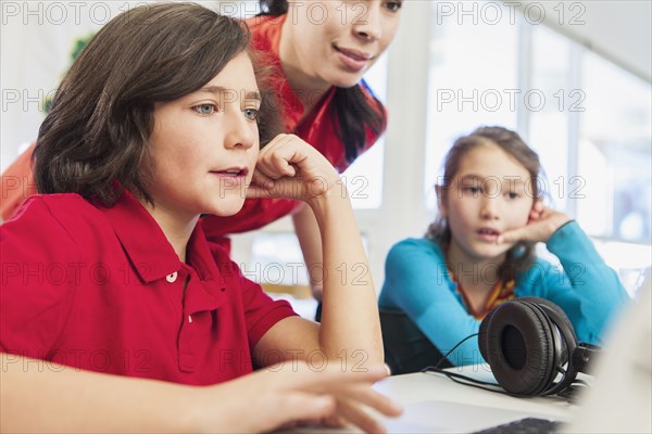 Teacher and students using laptop in library