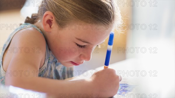 Caucasian girl coloring at table