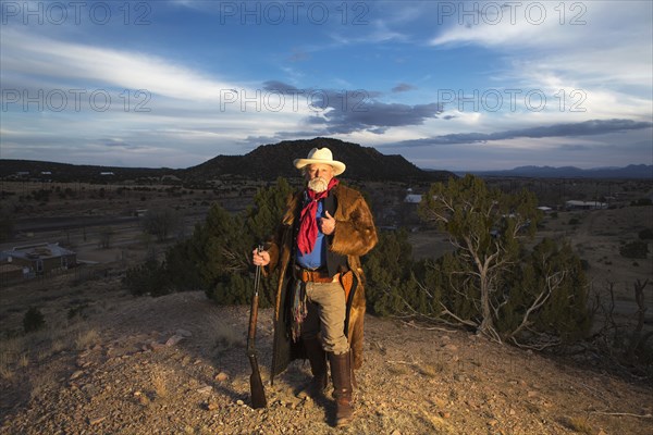 Caucasian man holding gun in dusty landscape