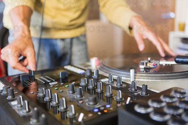 Mixed race disc jockey using turntable in studio