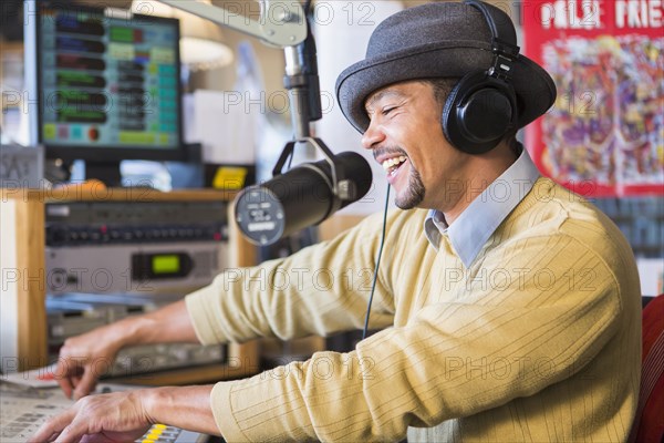 Mixed race disc jockey using turntable in studio