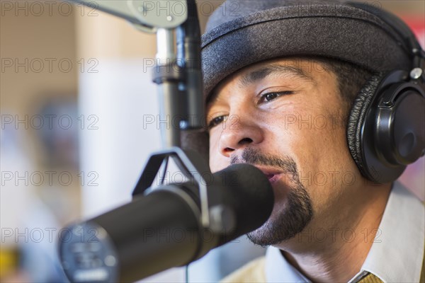 Mixed race disc jockey talking into mic in studio