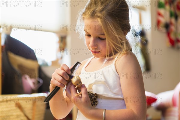 Caucasian girl combing doll's hair