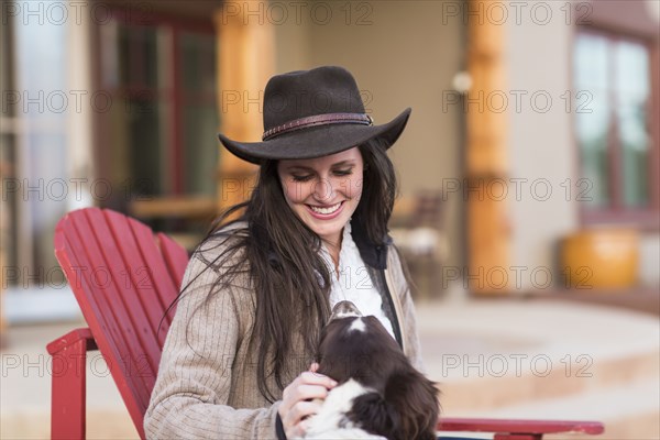 Caucasian woman petting dog in armchair