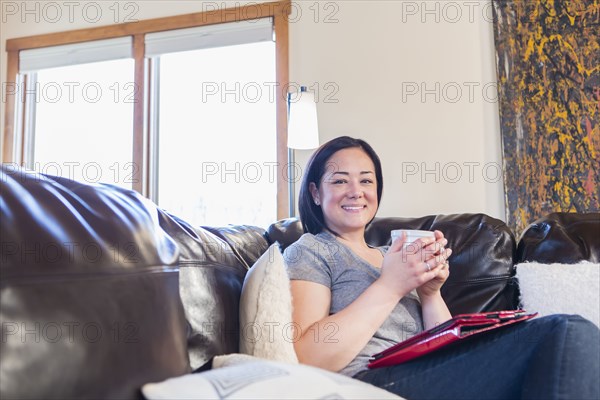 Mixed race woman using digital tablet on sofa