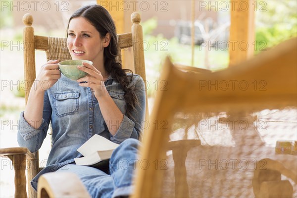 Caucasian woman having cup of coffee in rocking chair