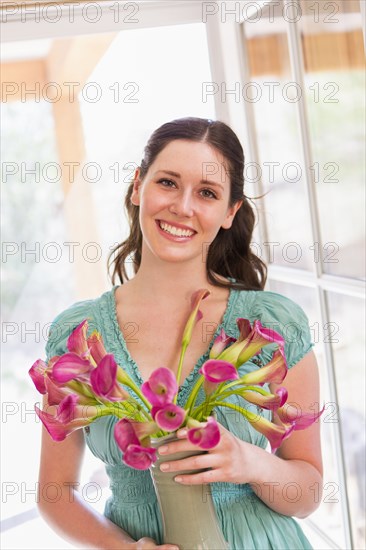 Caucasian woman holding vase of flowers