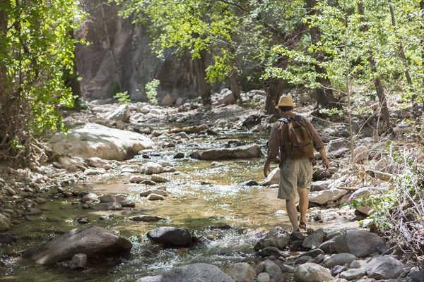 Caucasian man hiking along rocky creek
