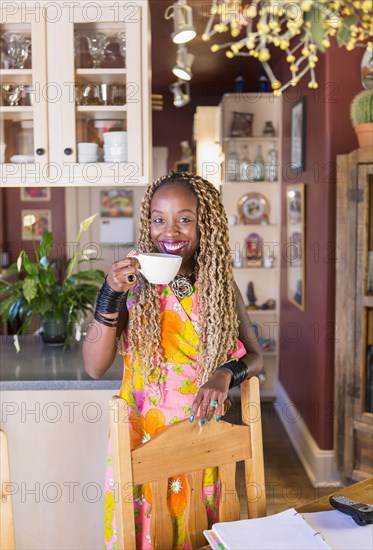 African American woman having cup of coffee in kitchen