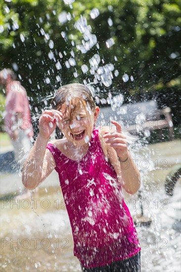 Caucasian girl playing in fountain