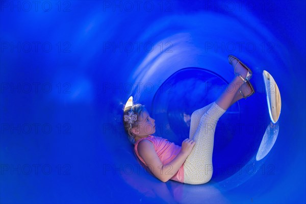 Caucasian girl sitting in plastic tunnel