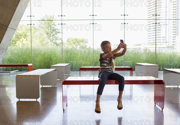 Caucasian girl taking self-portrait in lobby