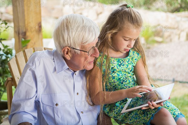 Caucasian man using digital tablet with granddaughter