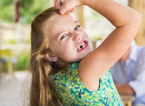 Caucasian girl showing missing teeth and flexing biceps