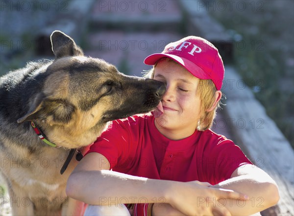 Dog licking Caucasian boy's face