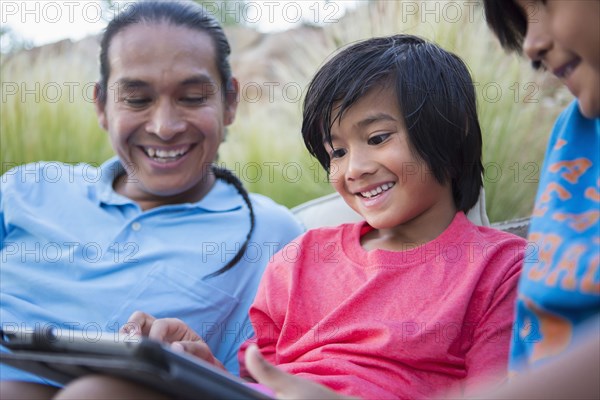 Family using digital tablet outdoors