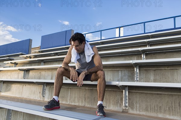 Hispanic athlete resting on bleachers