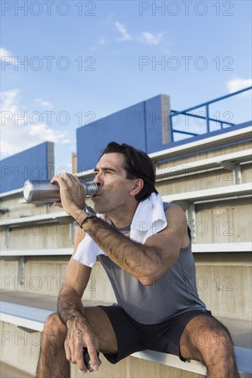 Hispanic athlete resting on bleachers