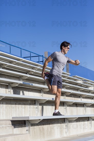 Hispanic athlete stretching on bleachers