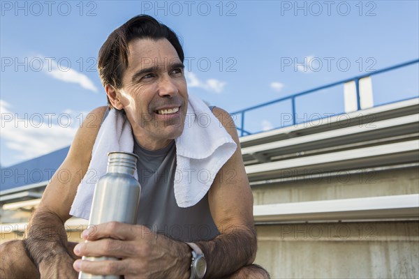 Hispanic man resting on bleachers
