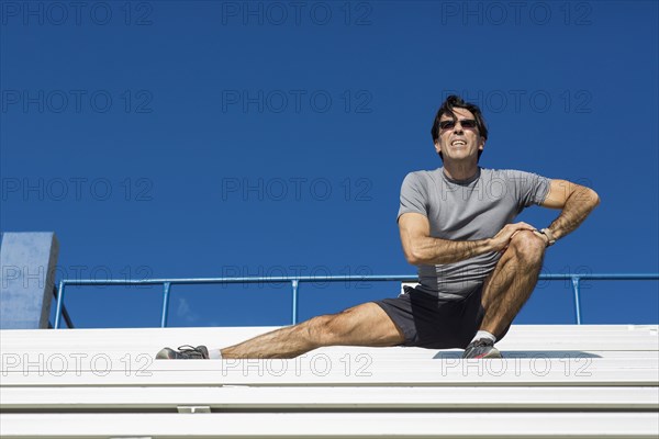 Hispanic athlete stretching on bleachers