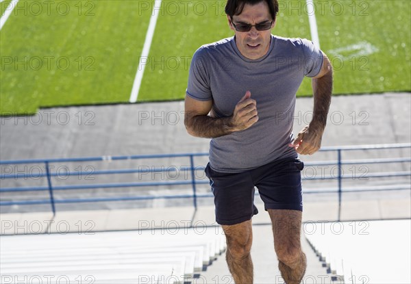 Hispanic athlete running on bleacher steps