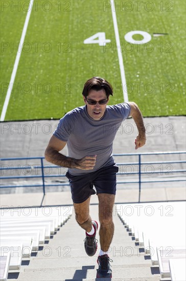 Hispanic athlete running on bleacher steps