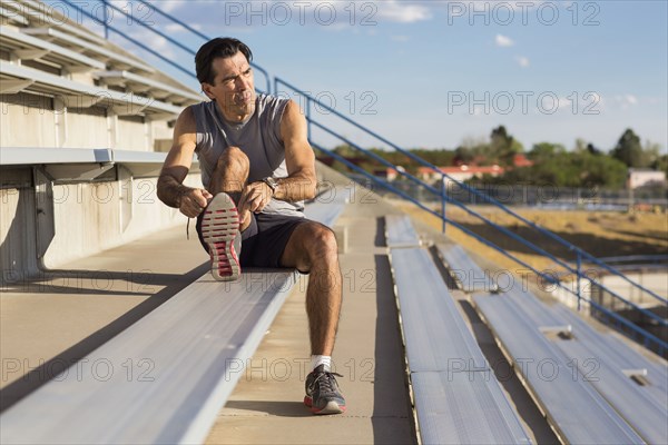 Hispanic athlete resting on bleachers