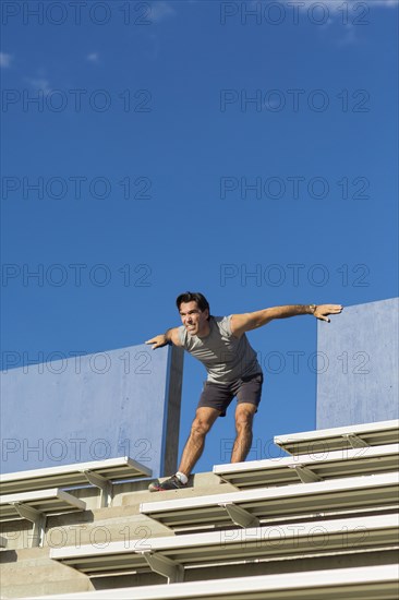 Hispanic athlete stretching on bleachers