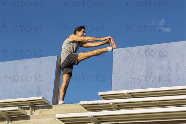 Hispanic athlete stretching on bleachers