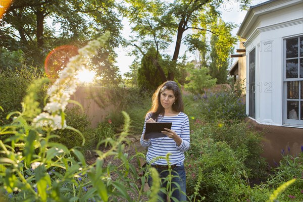 Hispanic woman sketching flowers in garden